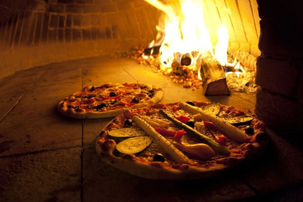 Deux pizzas en train de cuire dans un four à bois.